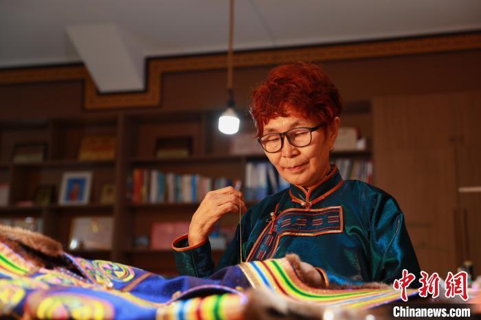 图为娜仁其其格正在手工缝制传统蒙古族服饰　陈坤　摄